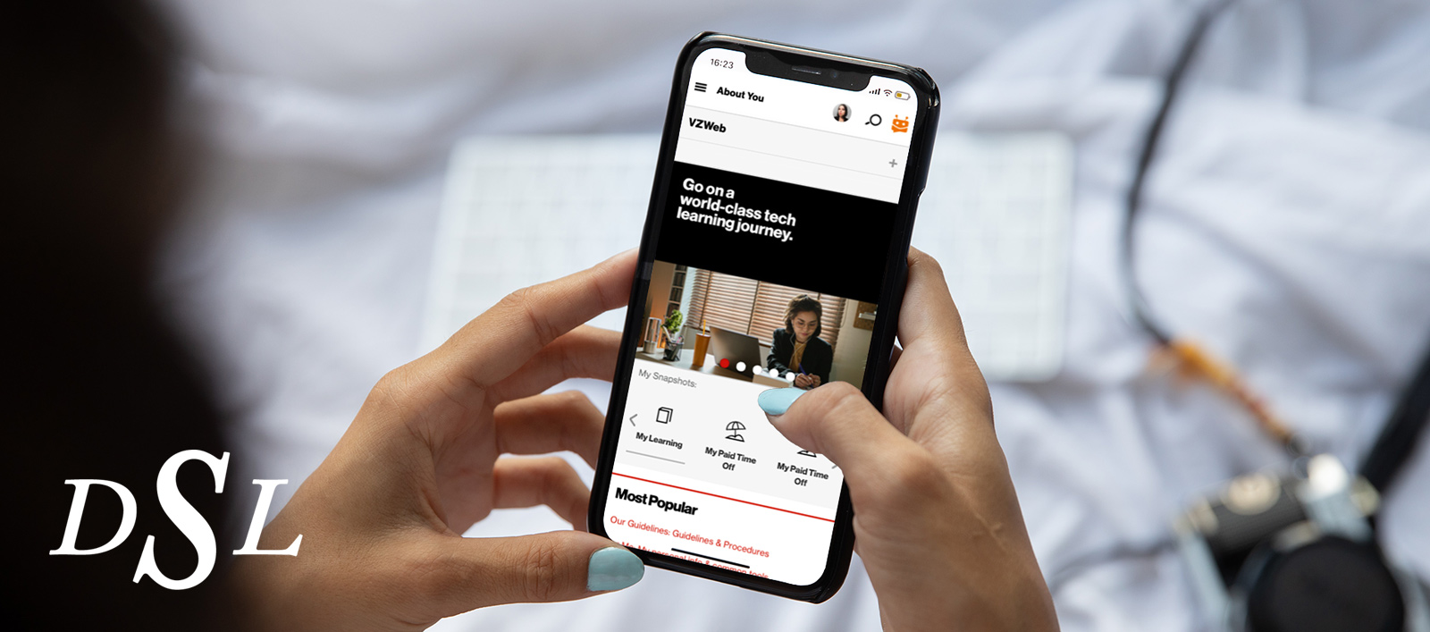 A woman with turquoise nails holding an iPhone while browsing the About You mobile page.